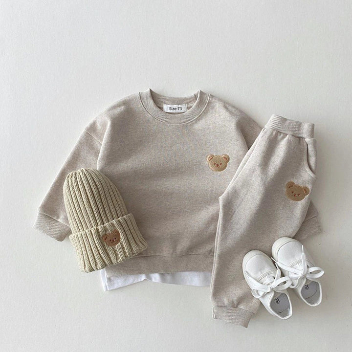 Gray bear-patch sweatshirt and pants styled with a beige ribbed hat and white lace-up shoes