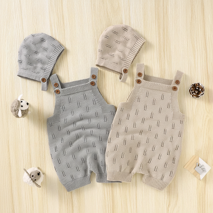 Gray and beige knitted baby overalls with coordinating hats laid flat on a pale wood surface.