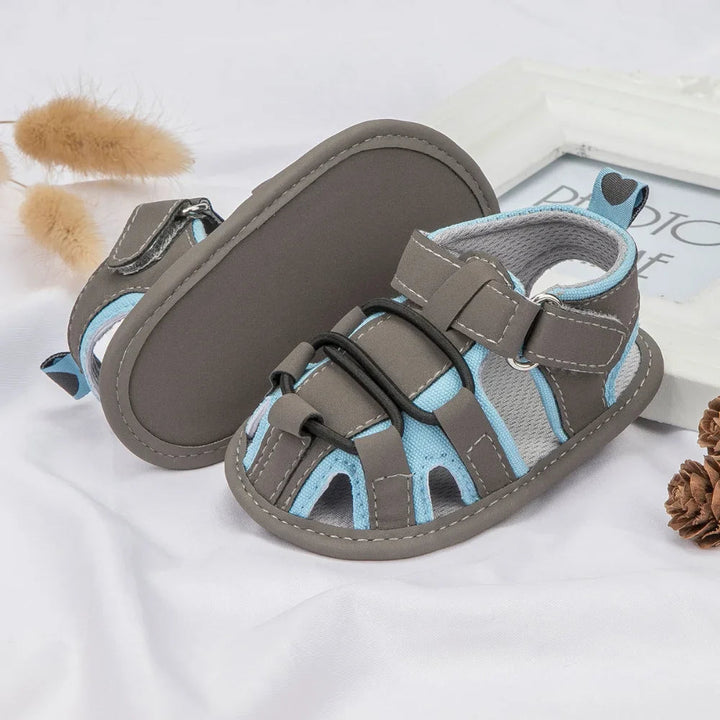 Gray and light blue baby sandals showing the openwork upper and smooth sole