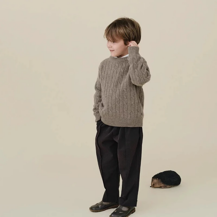 Child wearing a gray cable-knit sweater with black pants