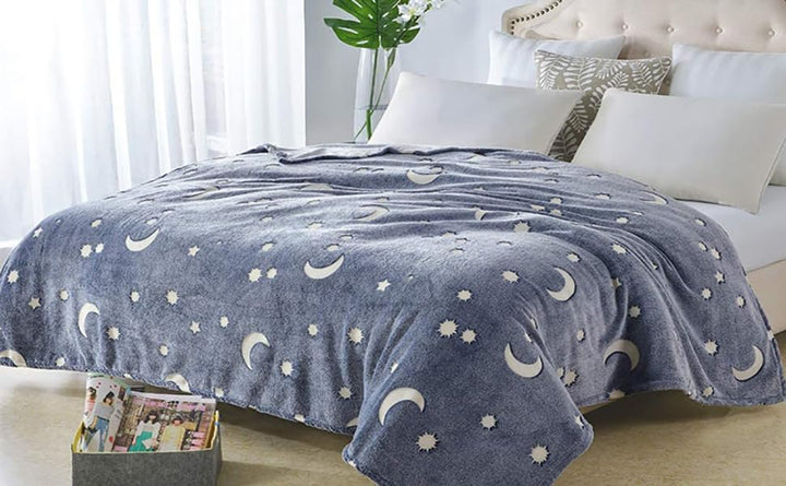Gray celestial-pattern blanket spread across a bed in a bright bedroom