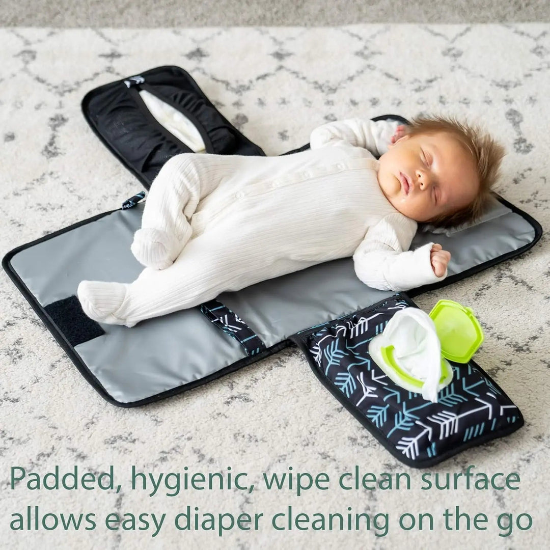 Baby lying on an open gray changing mat with a wipes packet in the side pocket.