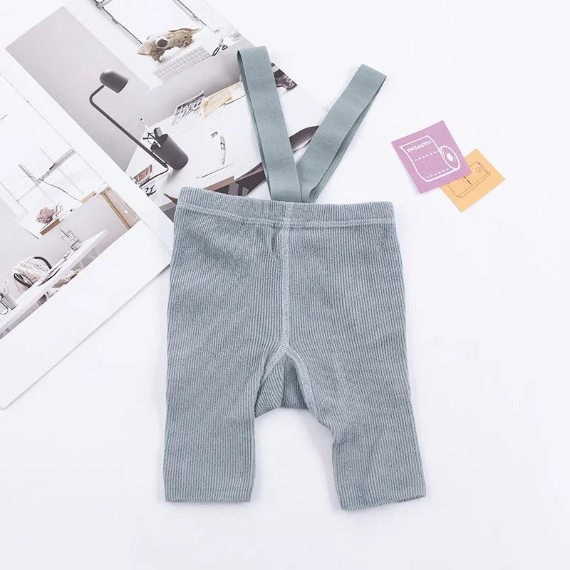 Gray ribbed suspender shorts laid flat with matching shoulder straps.