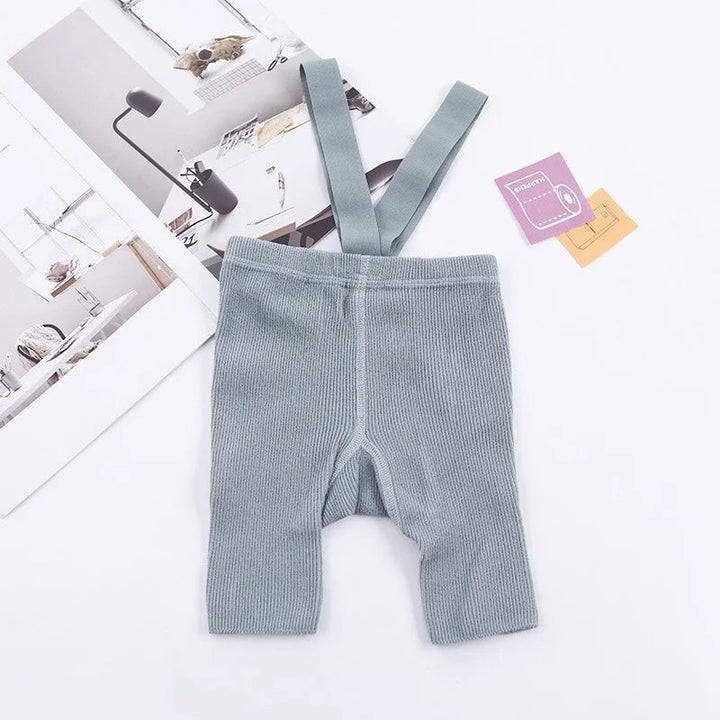 Gray ribbed suspender shorts laid flat with matching shoulder straps.