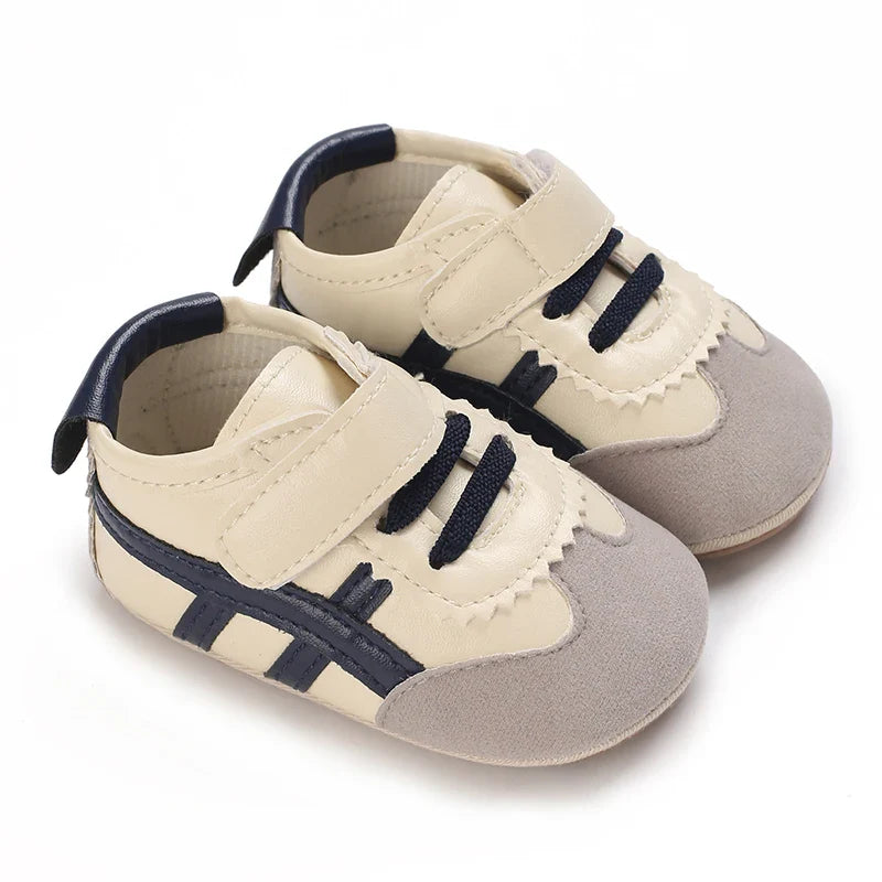 Cream and gray baby sneakers with navy side stripes and strap closures