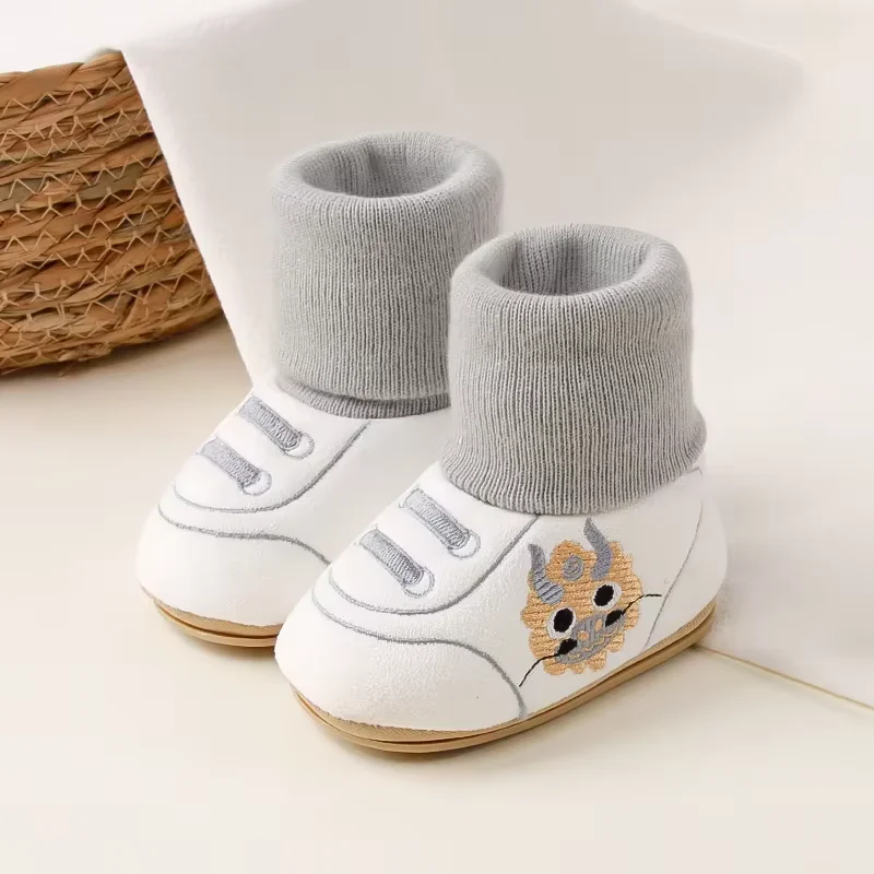 Pair of white baby shoes with gray knit cuffs and animal side motifs.
