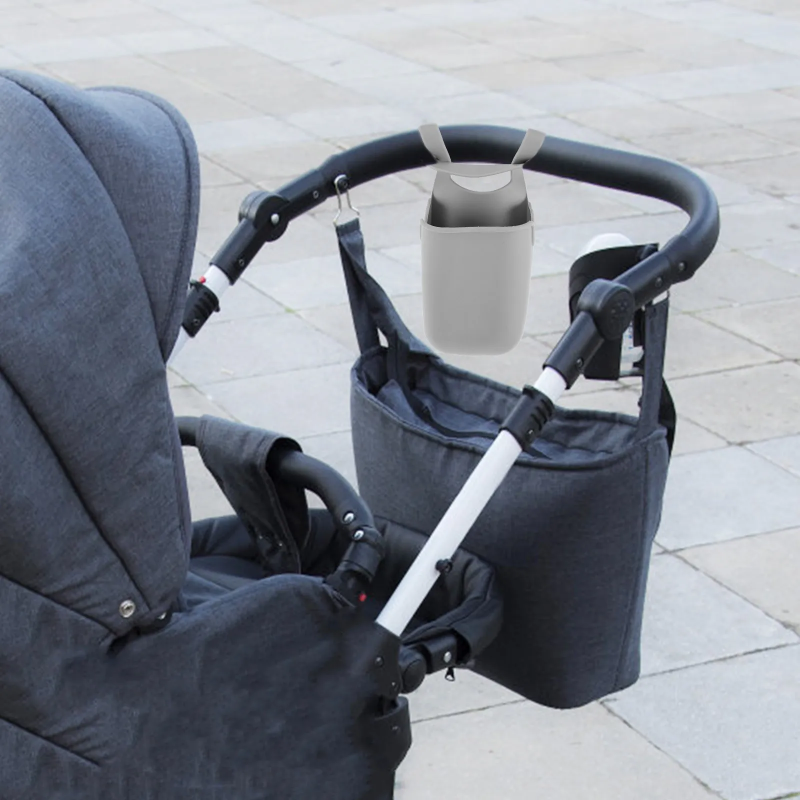 Gray silicone cup holder hanging from the handle of a gray stroller.