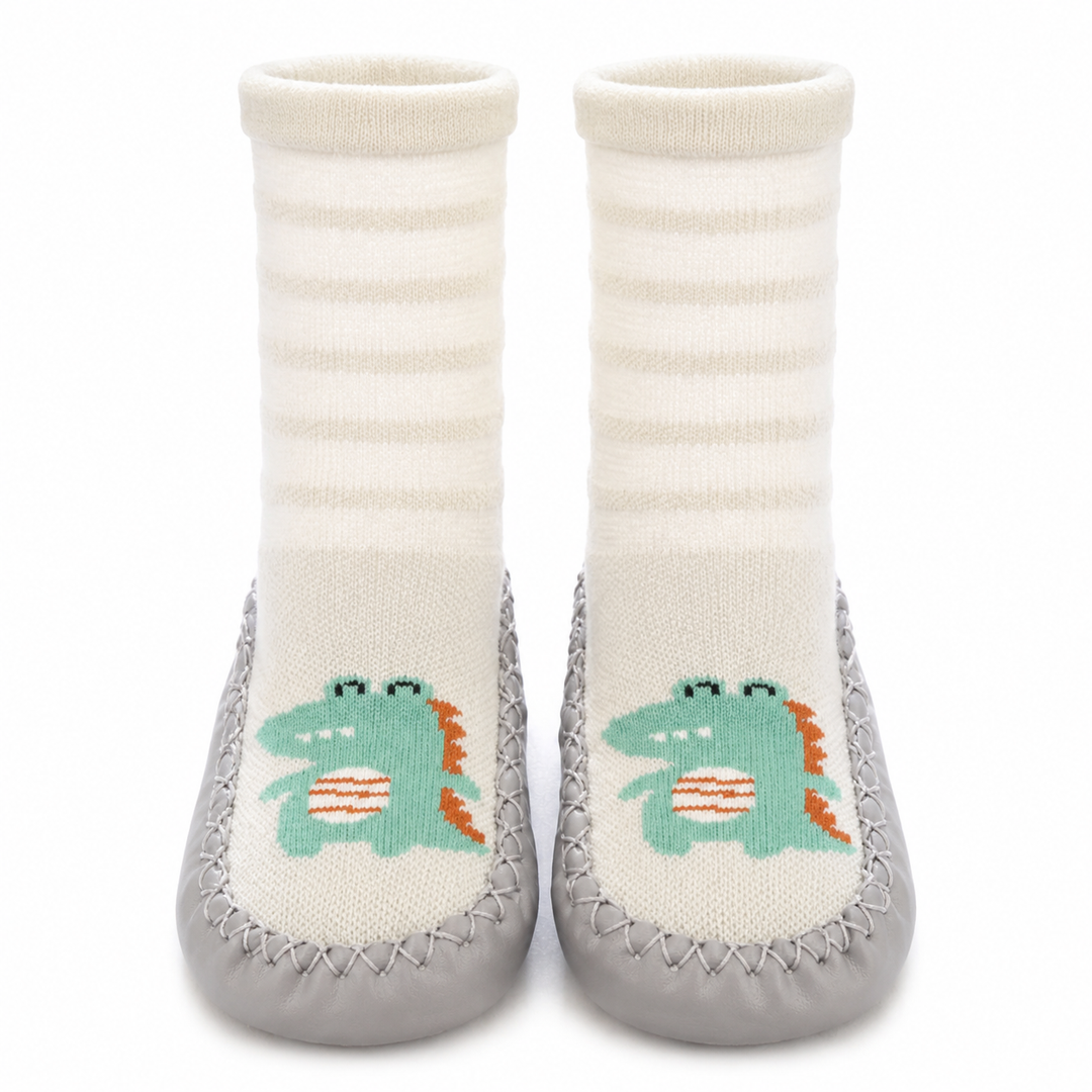 Sock shoes with white striped uppers, green dinosaur designs, and gray soles