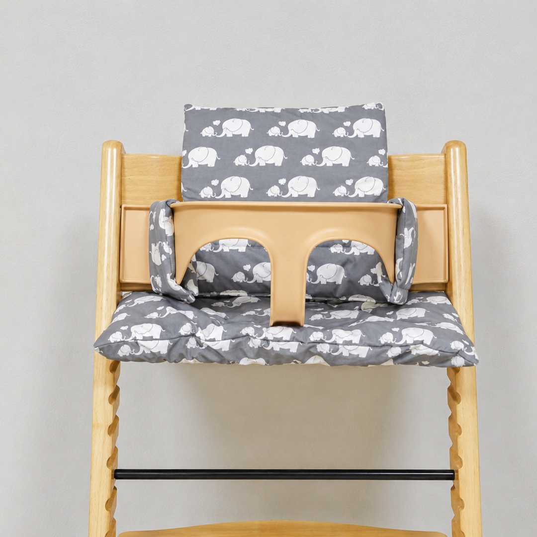 Gray high chair cushion with white elephant prints on a wooden chair