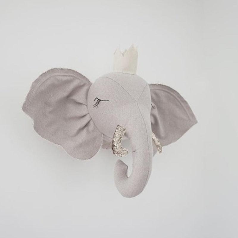 Gray elephant plush head displayed on a wall, with stitched closed eyes and textured tusks