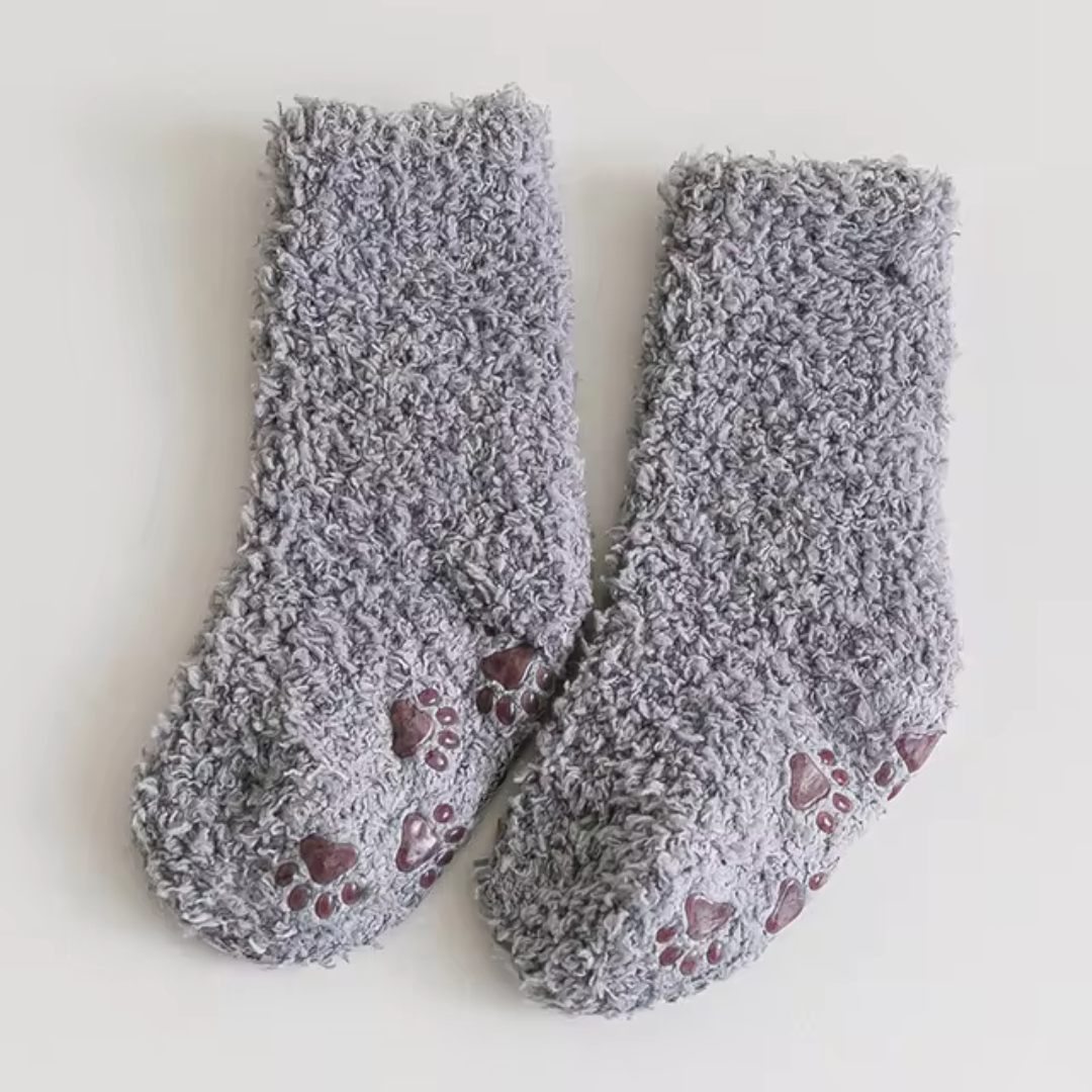 Gray fleece socks showing contrasting paw-print sole patterns.