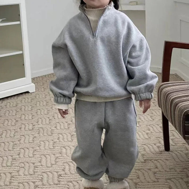Child wearing a gray fleece zip-neck top and matching pants with gathered cuffs