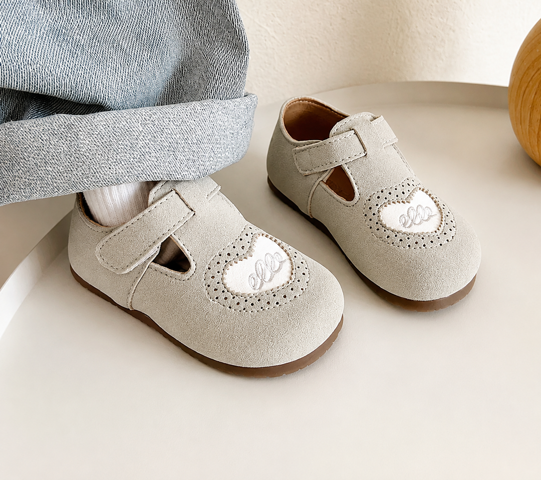 Gray heart-detail shoes with hook-and-loop straps beside a cuffed denim leg and white sock