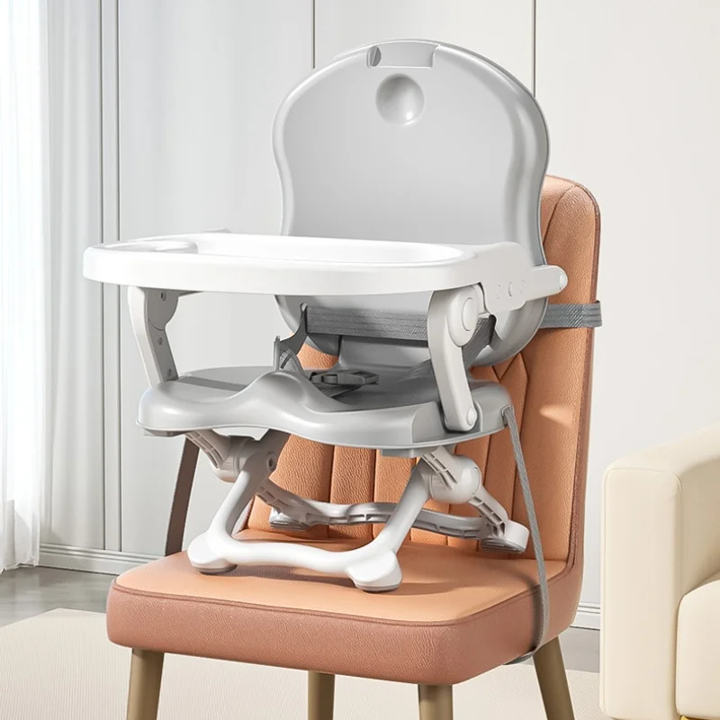 Gray high chair used as a booster on a dining chair with attachment straps