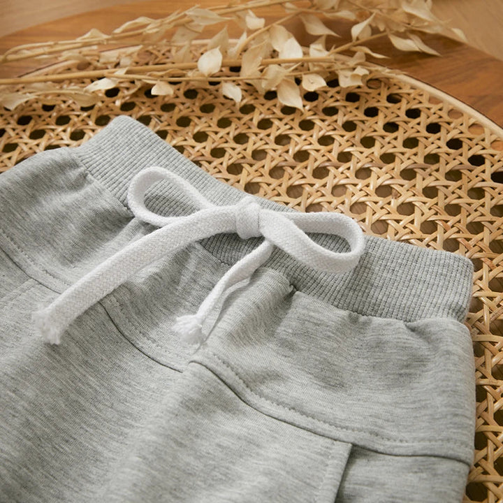 Gray pants with a ribbed waistband, white drawstring, and front pocket detail