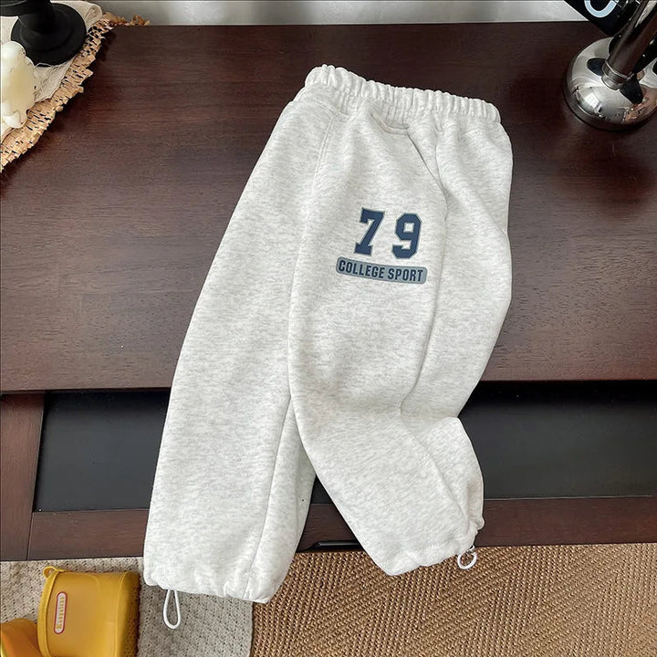Gray joggers with one leg folded across the other and a navy 79 graphic