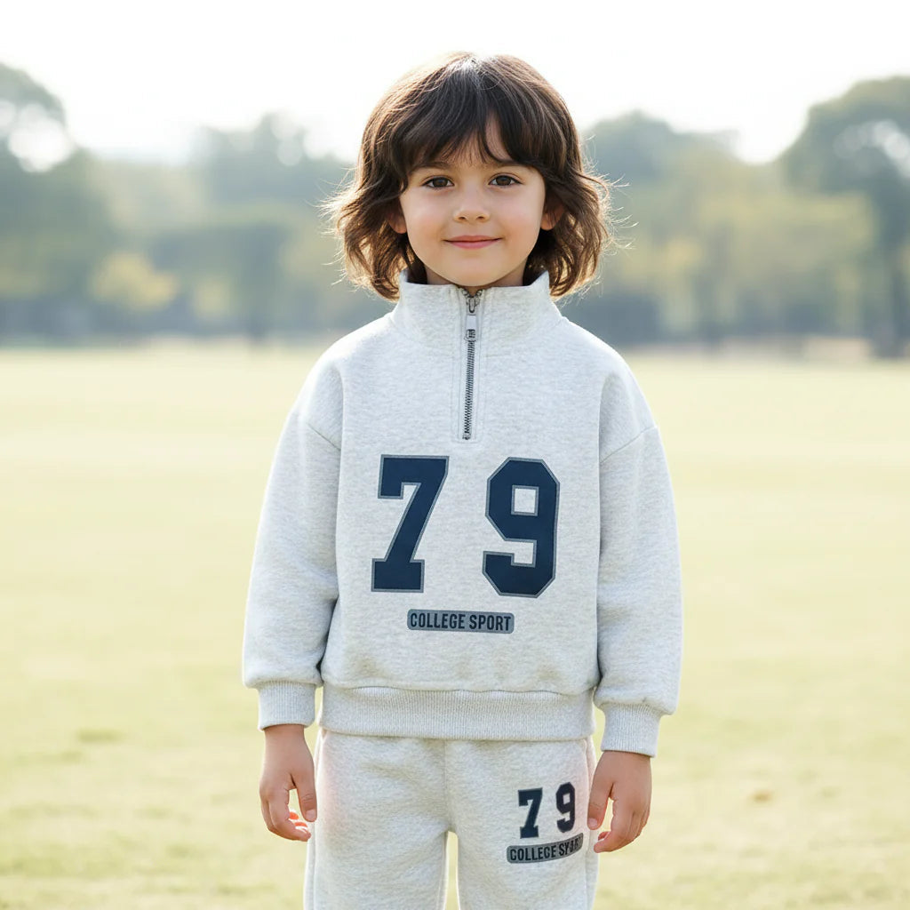 Child wearing a gray half-zip sweatshirt and matching joggers with navy 79 graphics outdoors