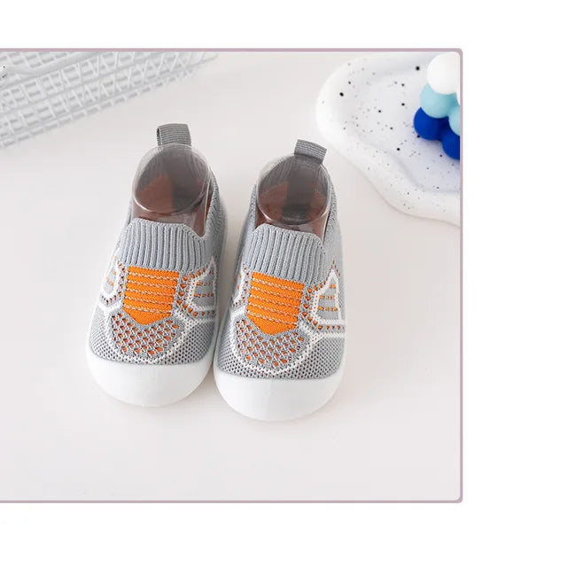 Pair of gray knit slip-on shoes with orange accents and white soles