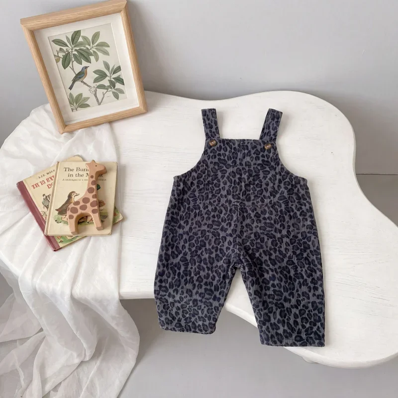 Gray leopard print overalls laid out on a curved white chair beside books