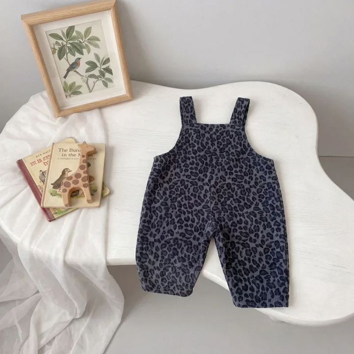 Full-length gray leopard print overalls displayed on a white chair