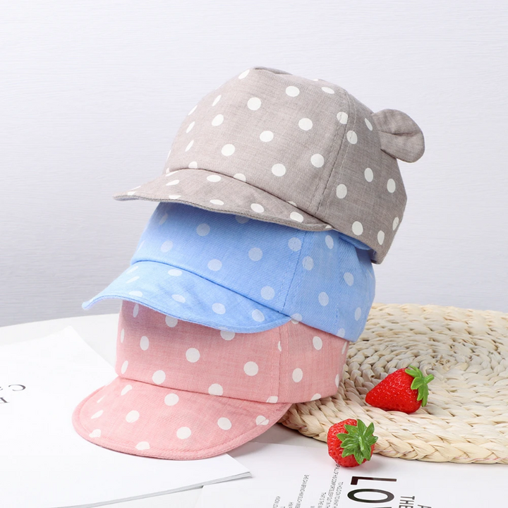 Gray, light blue, and pink polka dot caps stacked to show their colors and rounded ears.