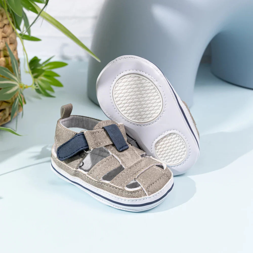Gray baby sandals with navy strap accents and a white sole with two textured pads