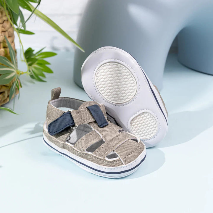 Gray baby sandals with navy strap accents and a white sole with two textured pads