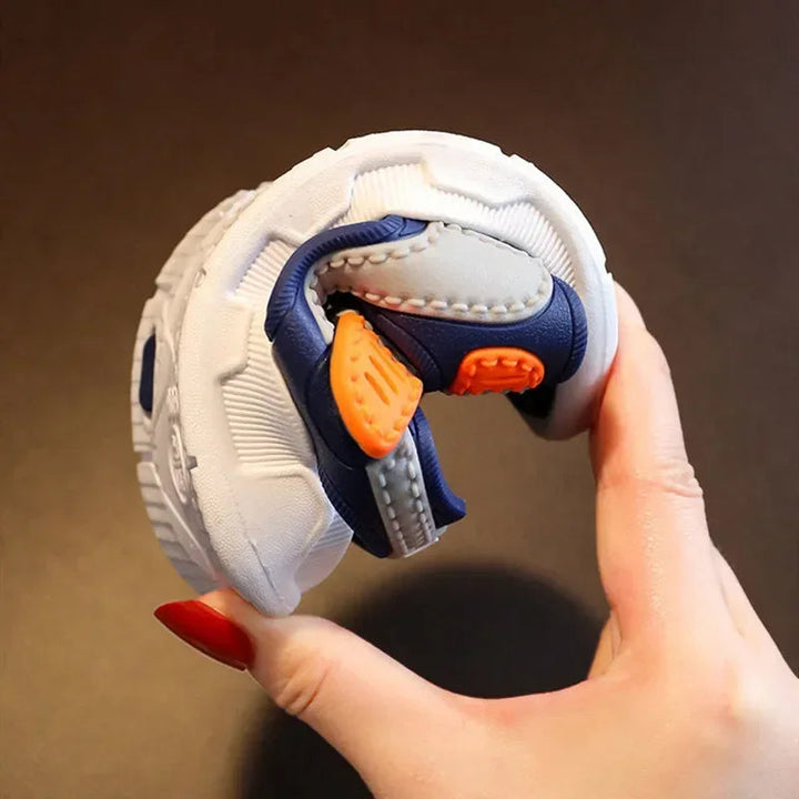 A gray and navy sandal bent by hand to demonstrate the flexible sole