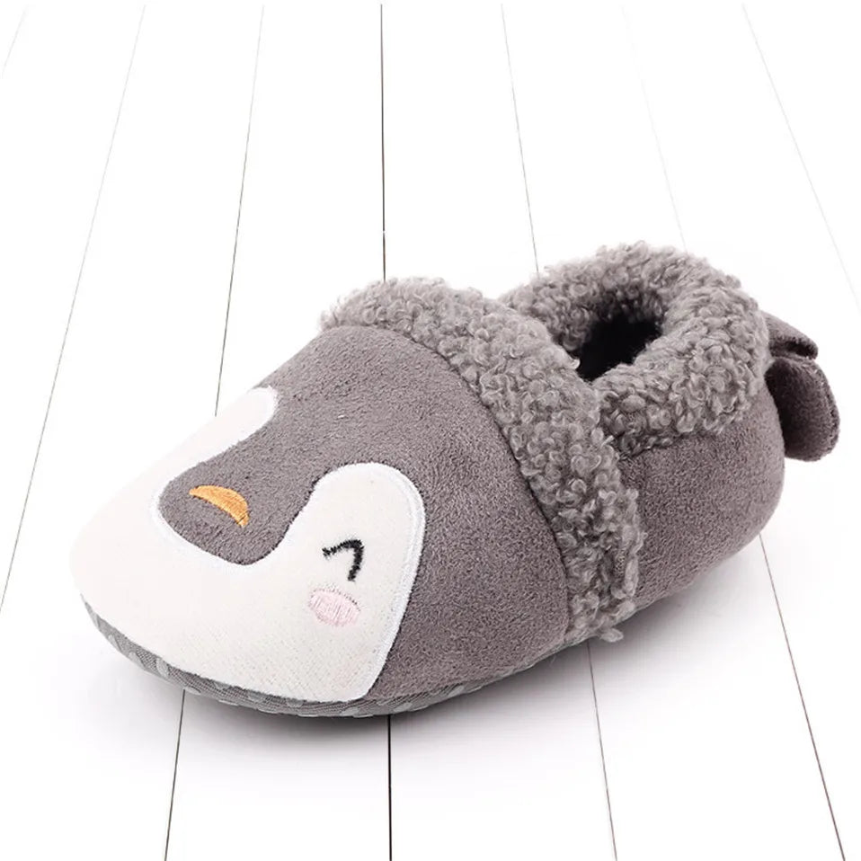 Gray penguin baby slipper with a white face and fuzzy cuff.