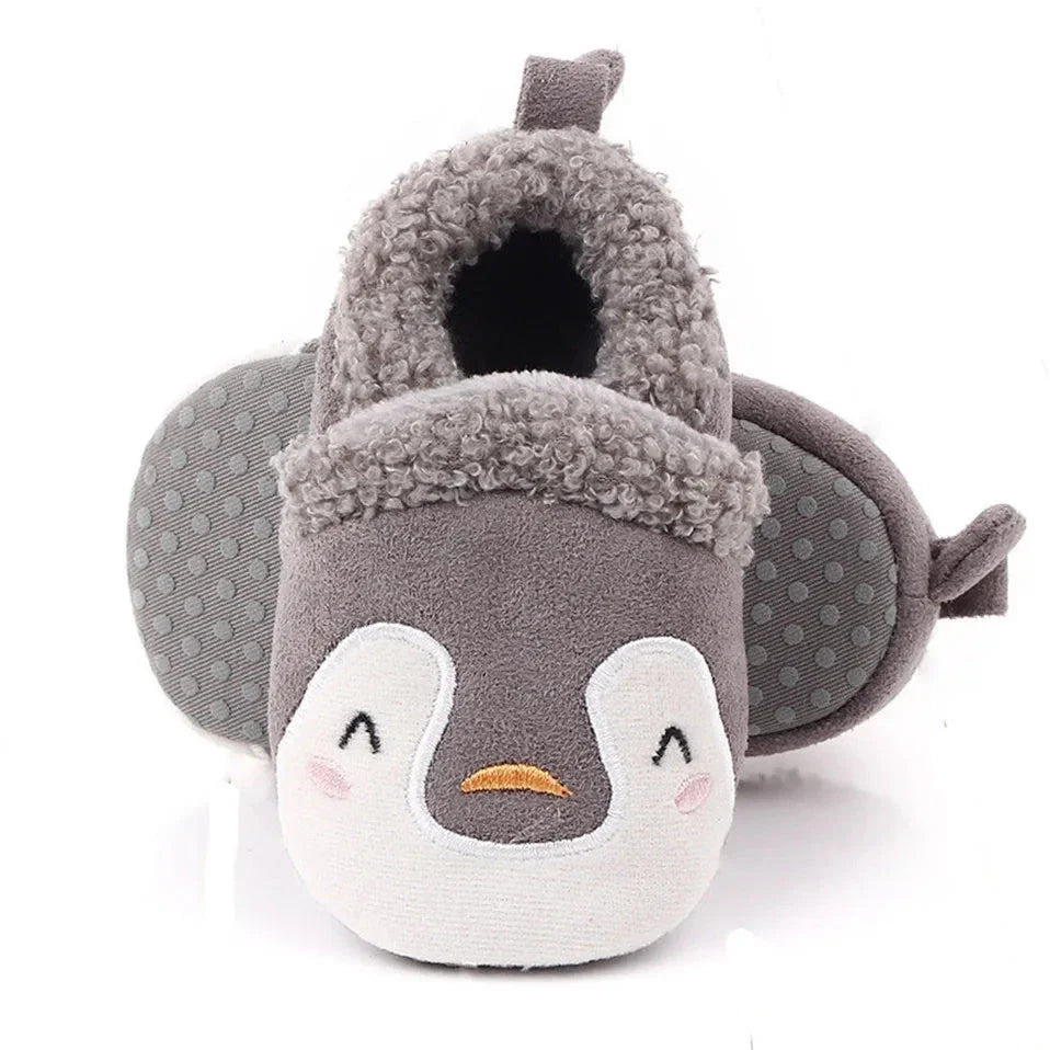 Gray penguin baby slippers with white faces and dotted soles.