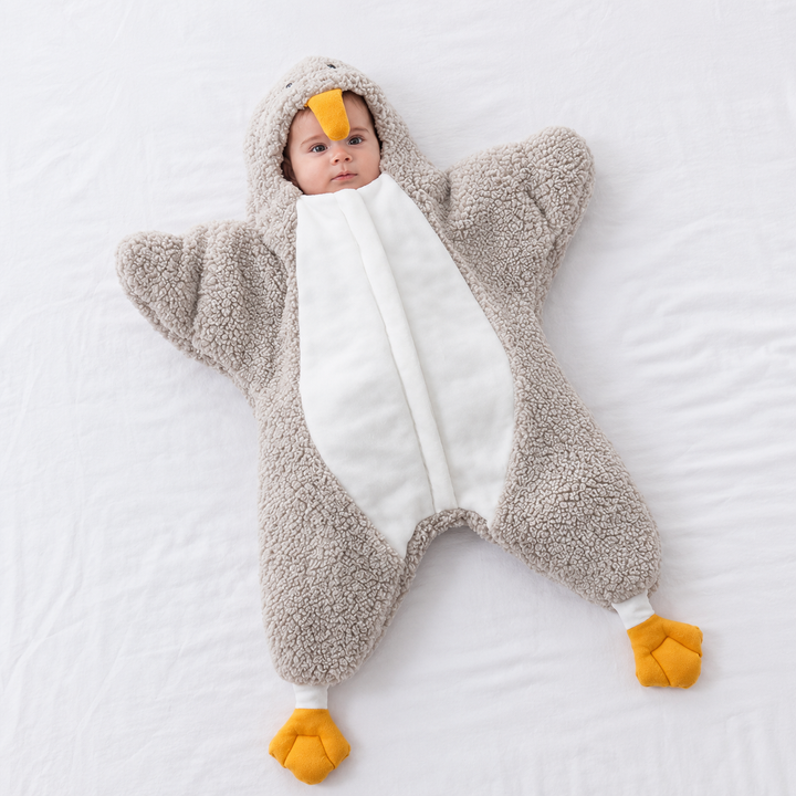 Baby wearing a gray penguin jumpsuit with a white front panel and yellow feet