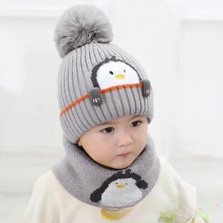 Child wearing a gray penguin pom-pom hat and matching scarf