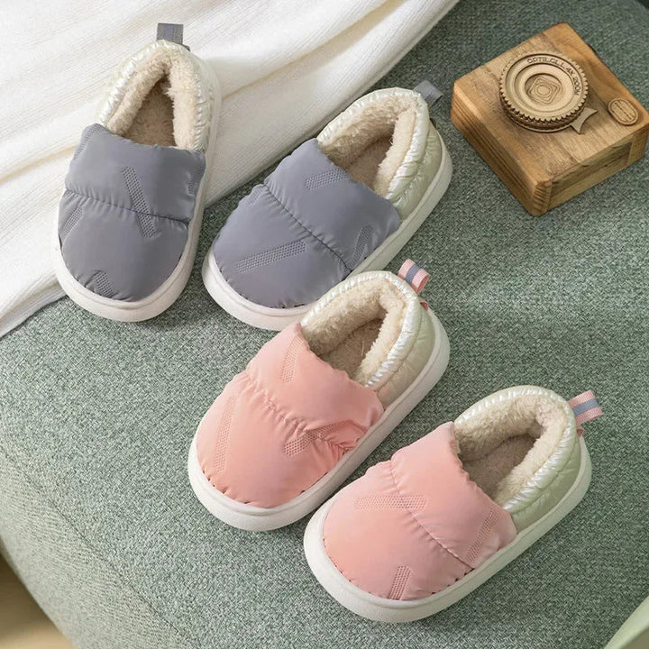 Gray and pink fleece-lined slippers arranged on a green rug
