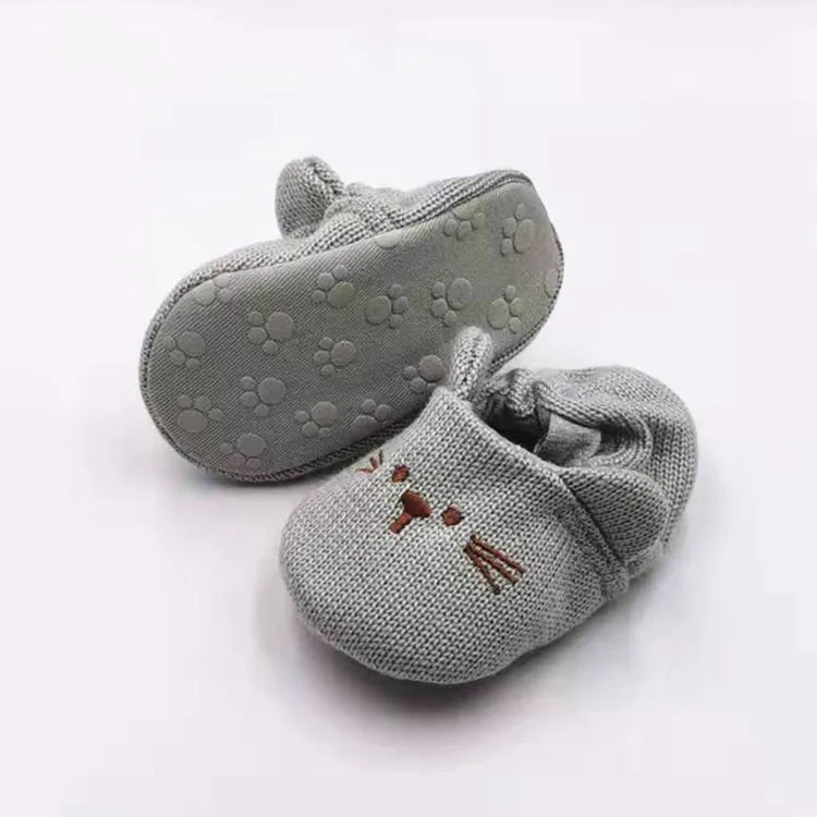 Gray rabbit baby slippers showing an embroidered face and a paw-patterned sole