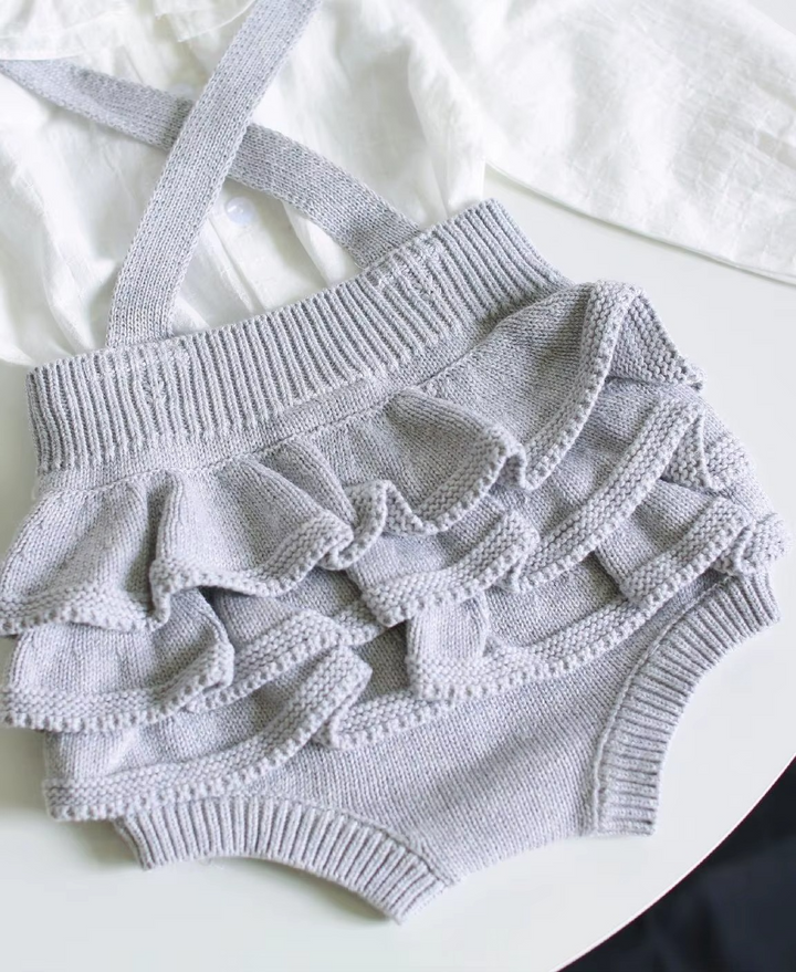 Light gray knit romper showing layered ruffles across the back