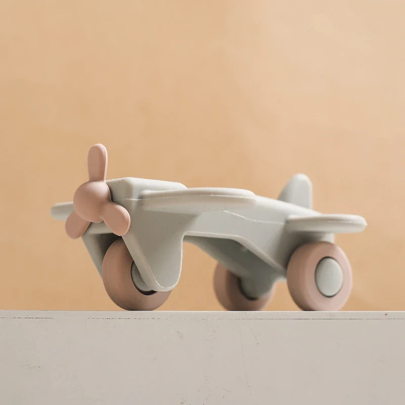 Gray silicone toy airplane with a pink propeller and wheels