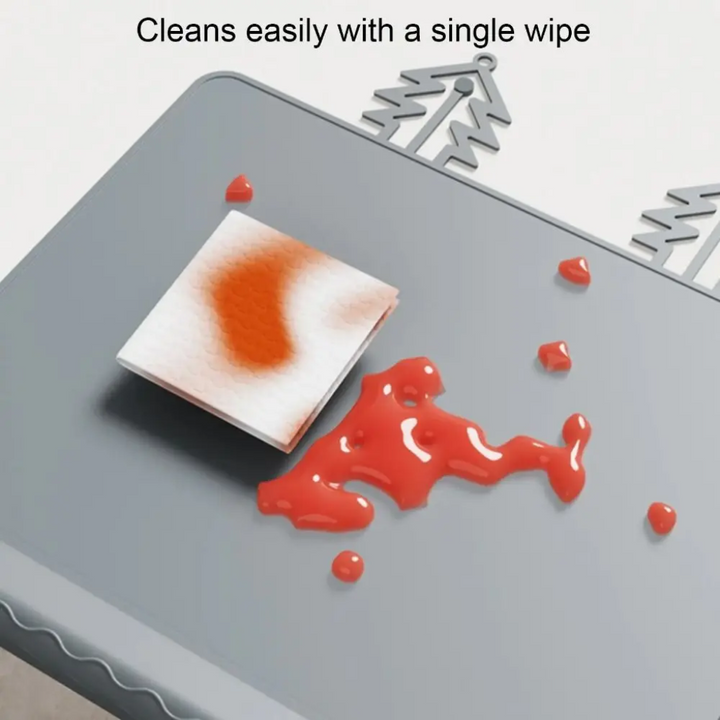 Gray silicone placemat with a cleaning cloth and spilled red sauce