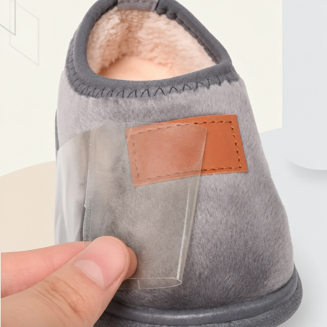 Gray slipper close-up showing a soft lining, tan front patch, and stitched opening