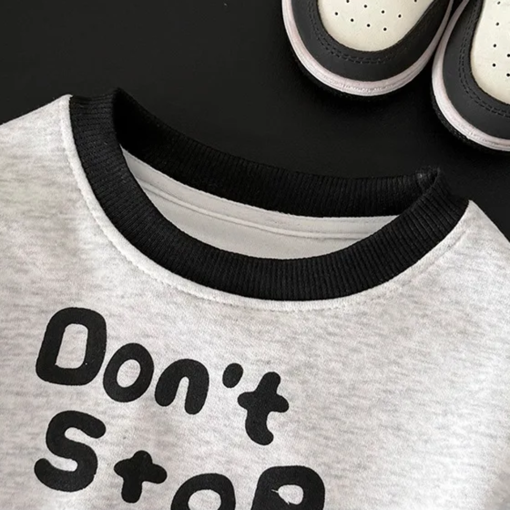 Close-up of the black ribbed round neckline on the gray graphic sweatshirt