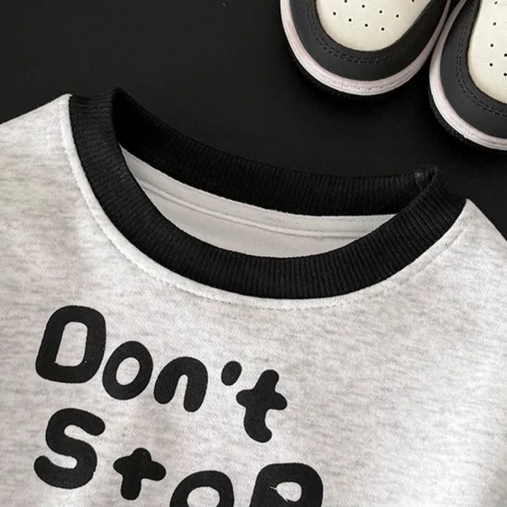 Close-up of the black ribbed round neckline on the gray graphic sweatshirt