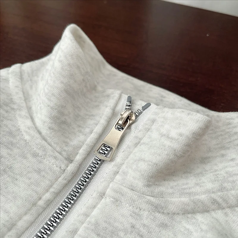 Close-up of the silver half zipper and gray sweatshirt collar