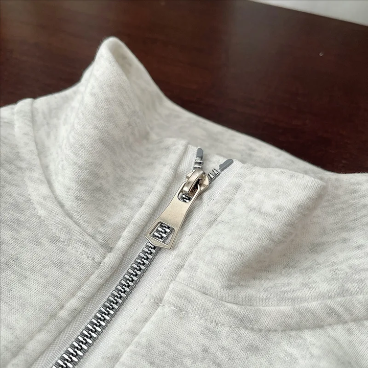Close-up of the silver half zipper and gray sweatshirt collar