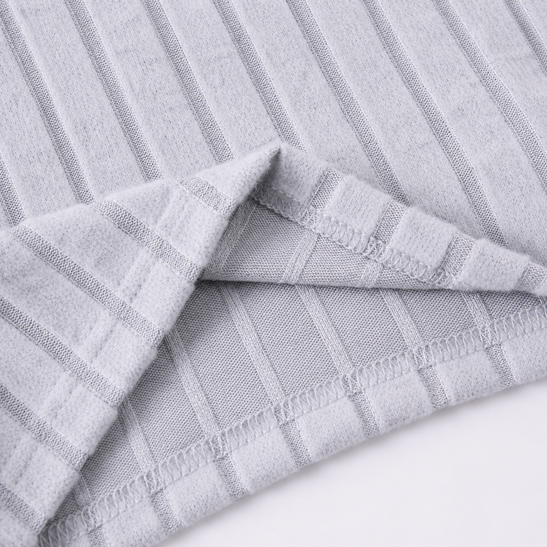 Close-up of the stitched hem and ribbed texture on the gray tracksuit fabric.