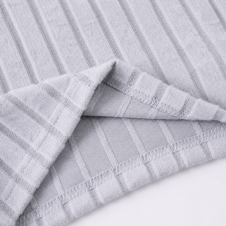 Close-up of the stitched hem and ribbed texture on the gray tracksuit fabric.