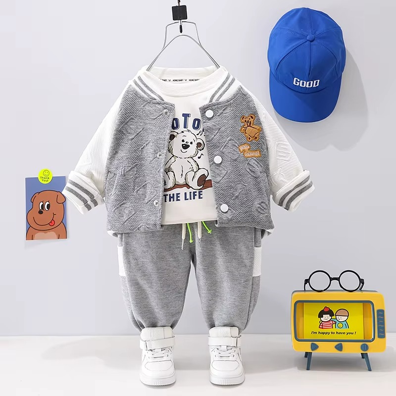 Gray-and-white varsity jacket with a graphic T-shirt and gray joggers, displayed beside a blue cap