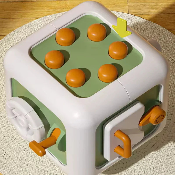 Green and white activity cube with six raised orange buttons and side controls