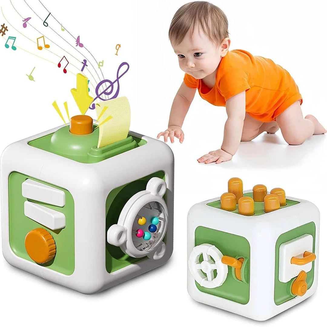 Green activity cube shown beside a crawling child, with buttons, a pull tab, and a bead spinner