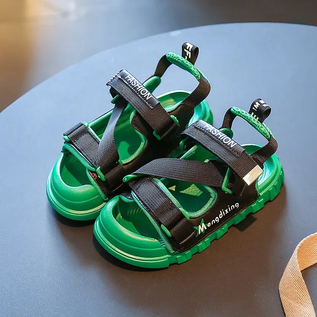 Green sandals on a table, with black adjustable straps and open-toe fronts.