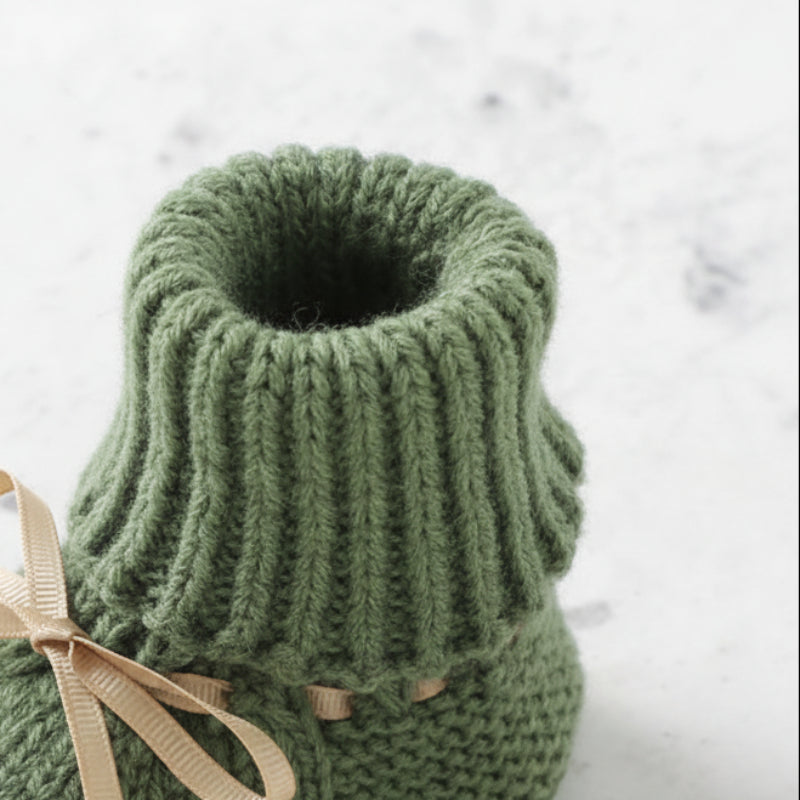 Close-up of the ribbed opening on a green knitted baby bootie