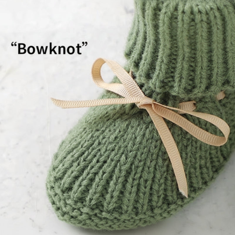 Beige ribbon bow detail on a green knitted baby bootie
